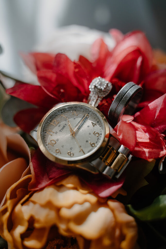 detail photo of rings and watch on top of a wedding bouquet 