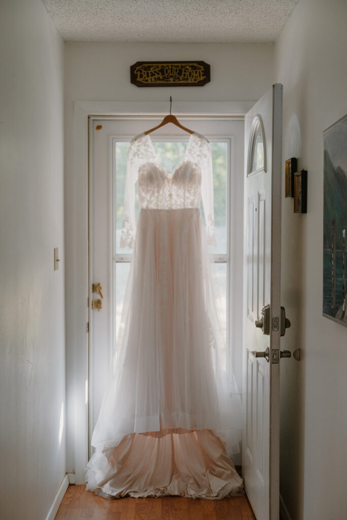 Photo of bride's dress hanging in front of a window