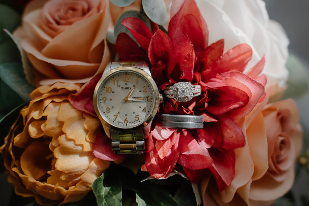 detail photo of rings and watch on top of a wedding bouquet 