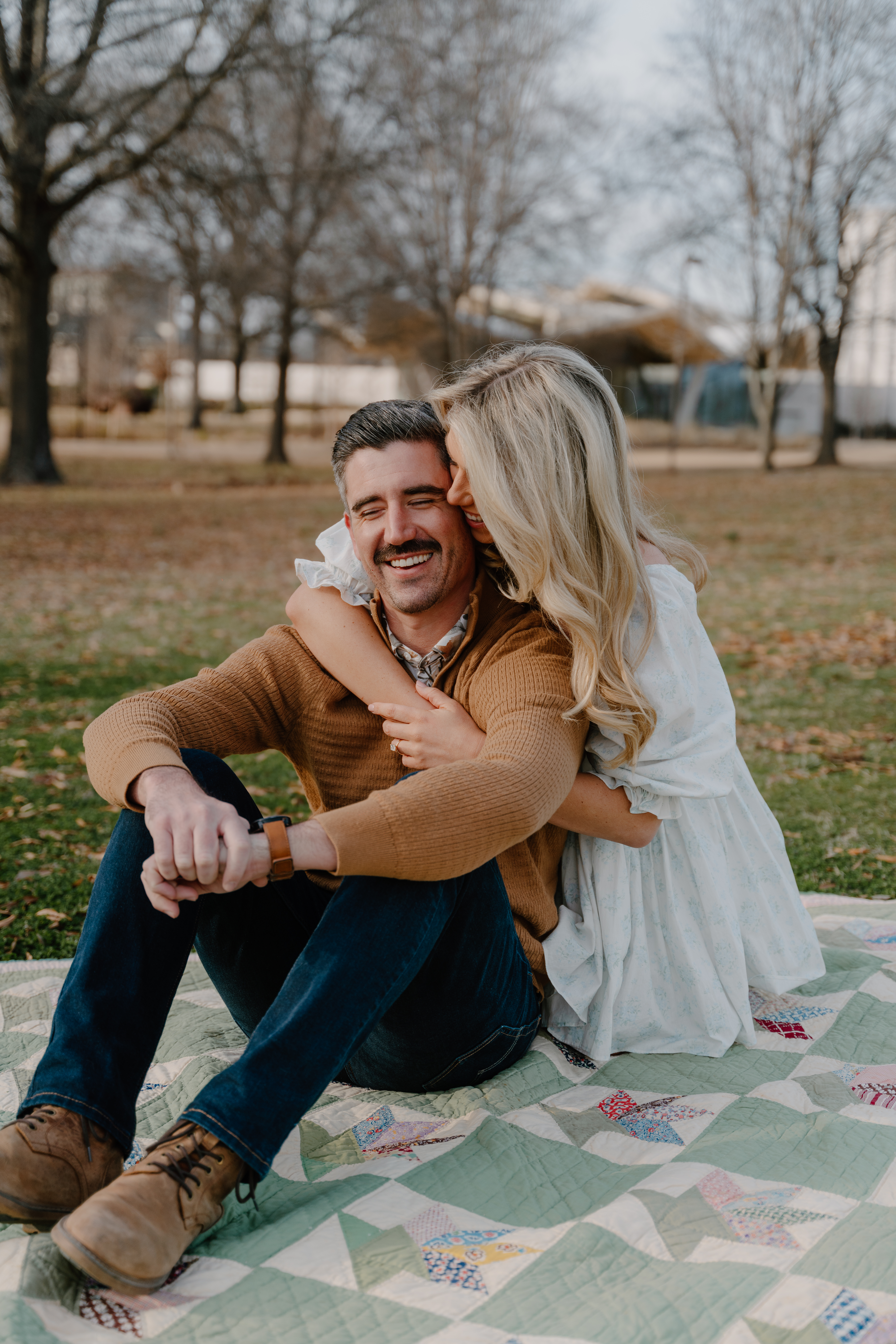 Photo of engaged couple sitting on a quilt at MacArthur Park in Little Rock, Arkansas
