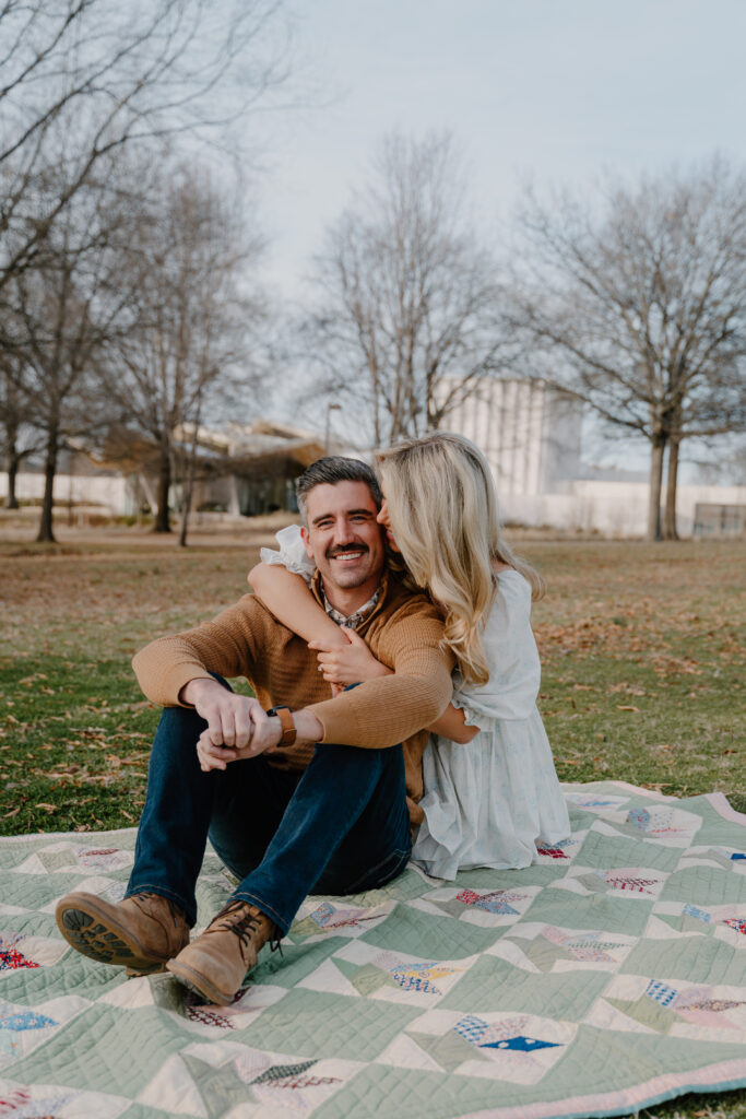 Photo of engaged couple sitting on a quilt at MacArthur Park in Little Rock, Arkansas