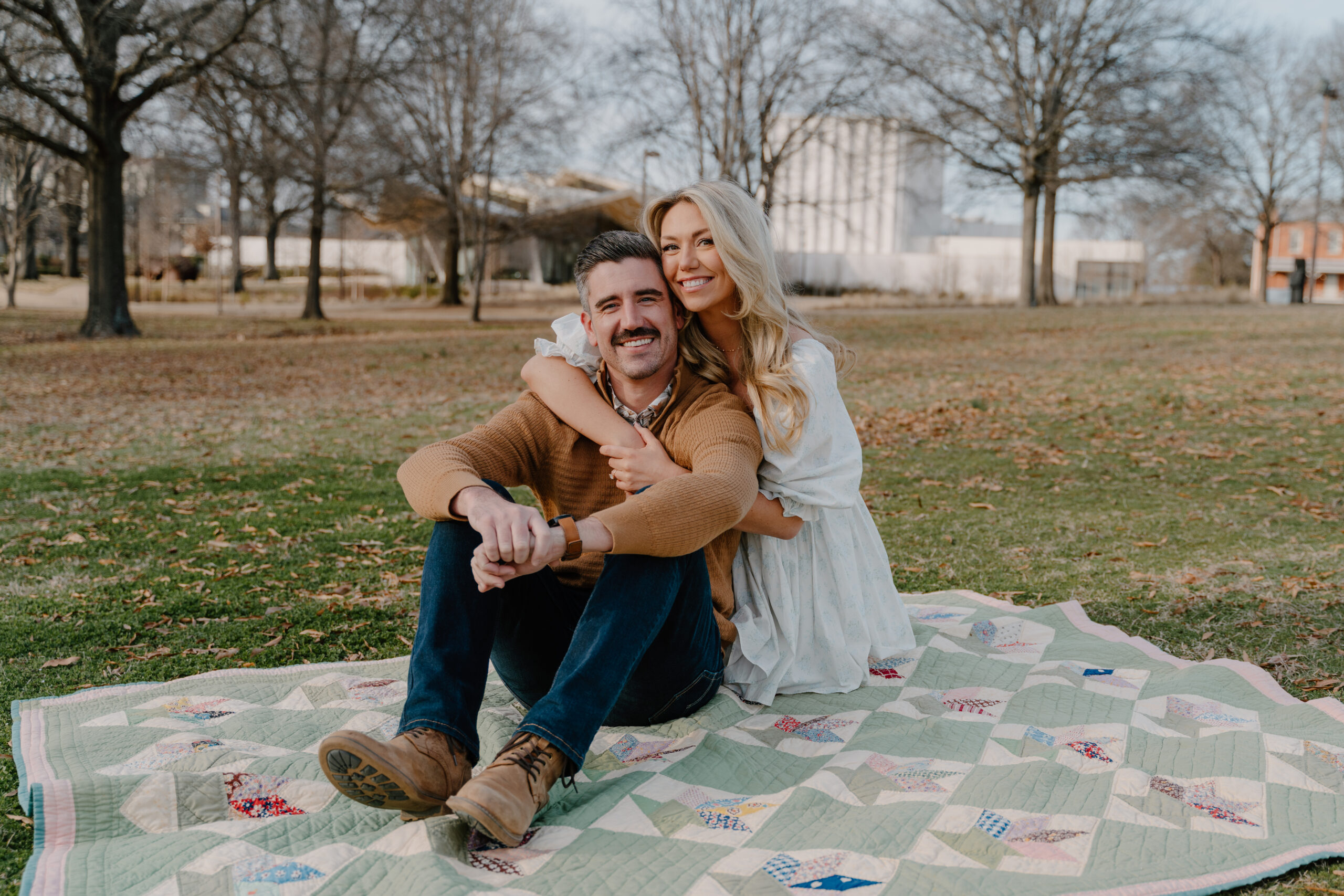 Photo of engaged couple sitting on a quilt at MacArthur Park in Little Rock, Arkansas