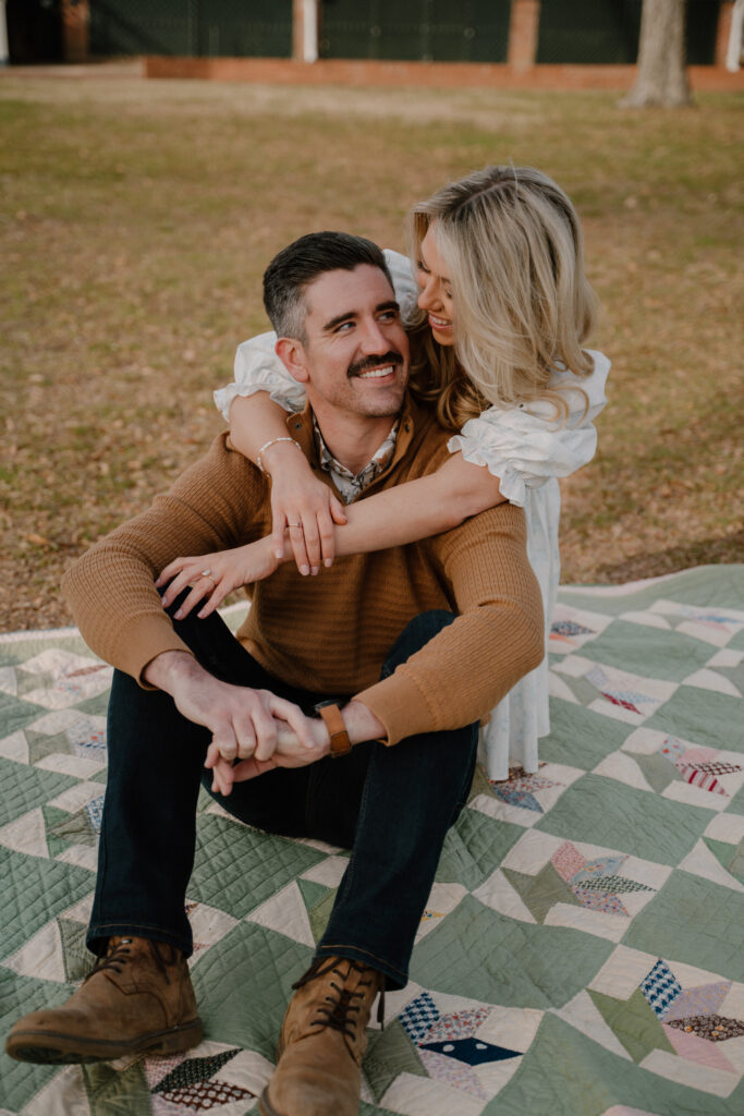 photo of engaged couple sitting on a quilt behind the Military History Museum in Little Rock