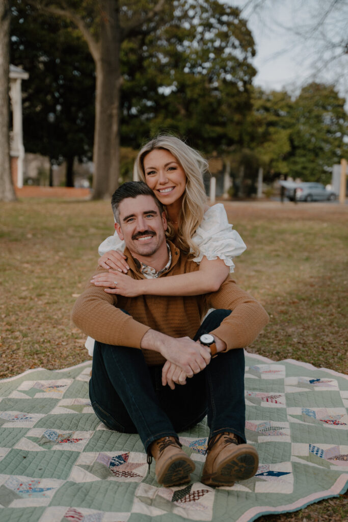 photo of engaged couple sitting on a quilt behind the Military History Museum in Little Rock