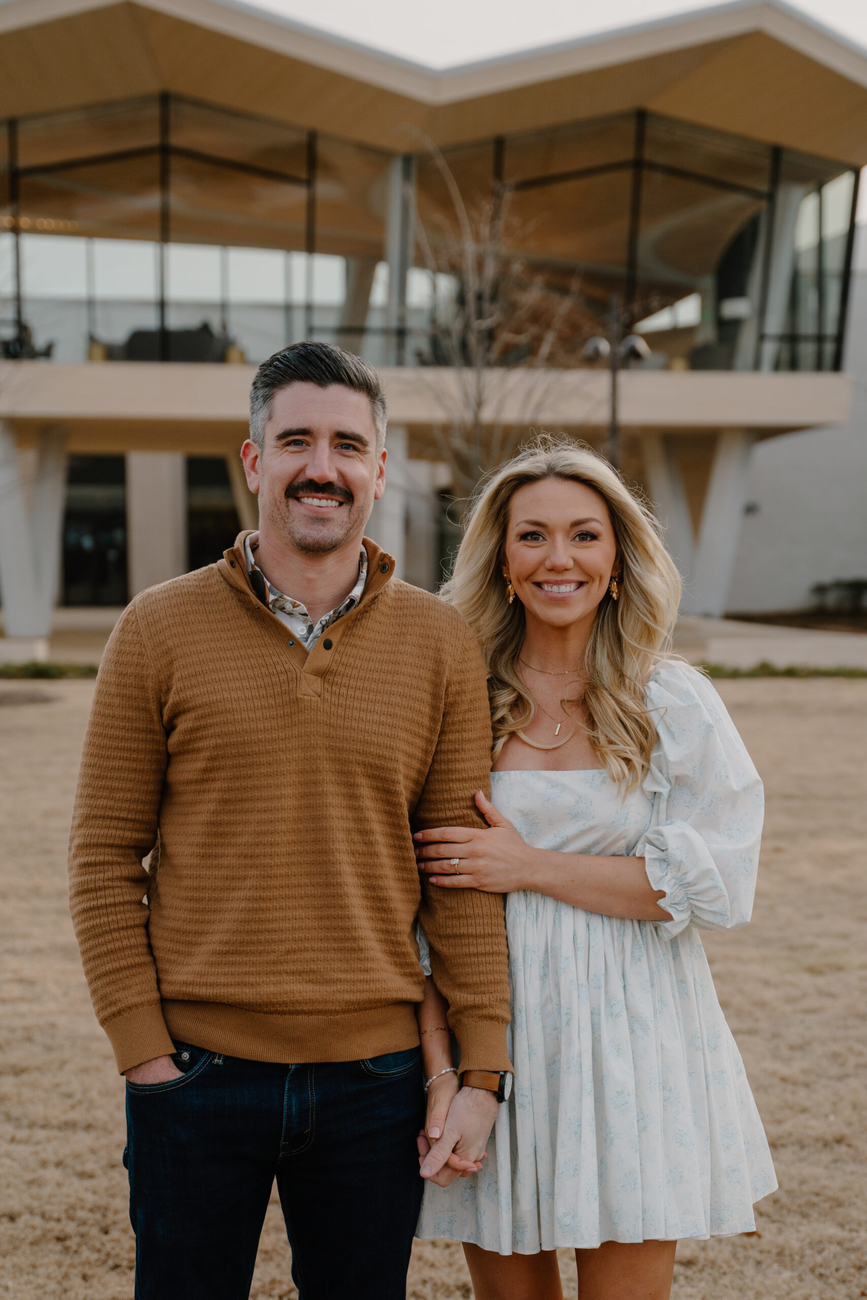 photo of engaged couple posing in front of the Arkansas Museum of Fine Art