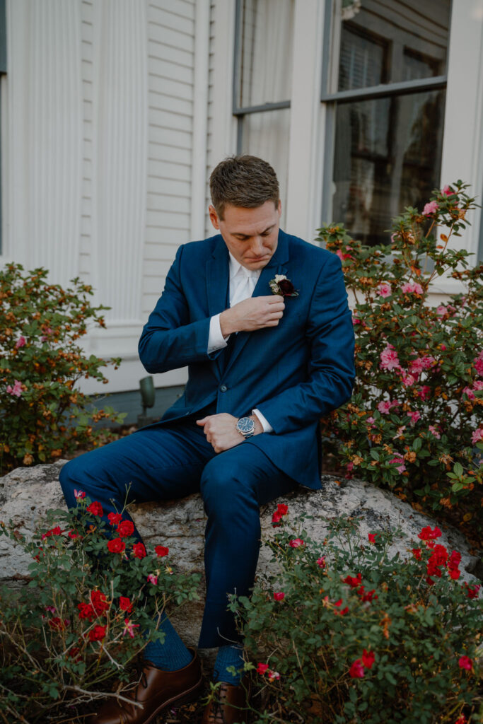 photo of groom posing messing with his boutonniere 