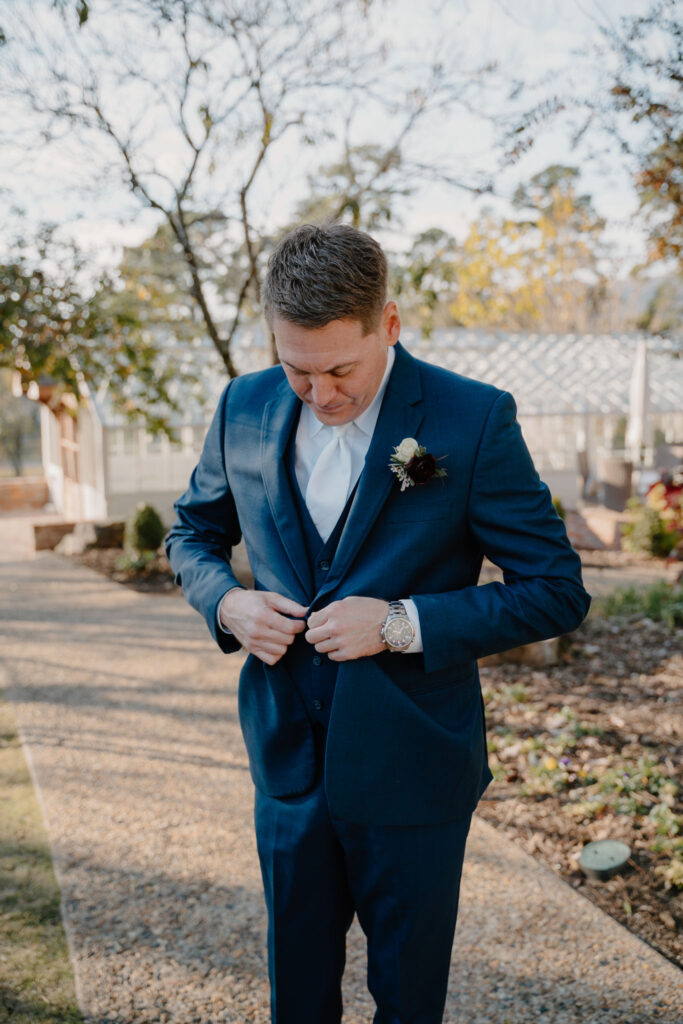 photo of groom buttoning his coat