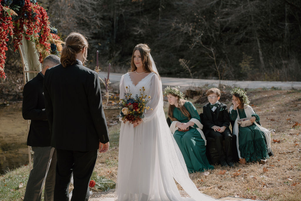 Photo of bride looking at her groom during the wedding ceremony in the woods