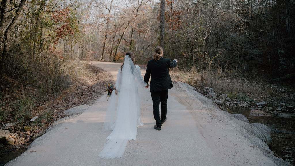 photo of bride and groom walking down a forrest path