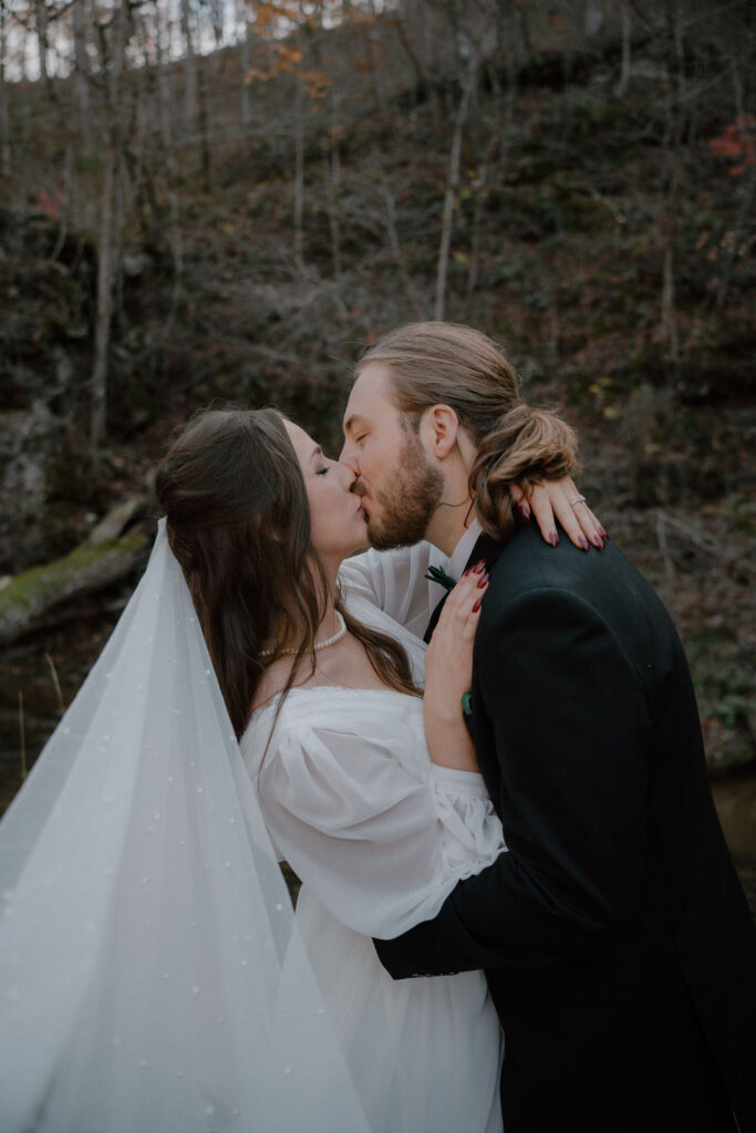 photo of bride and groom kissing in the woods of northwest Arkansas
