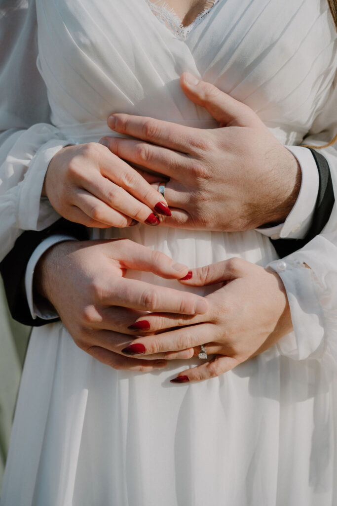 photo of bride and groom holding each other hands and wedding rings