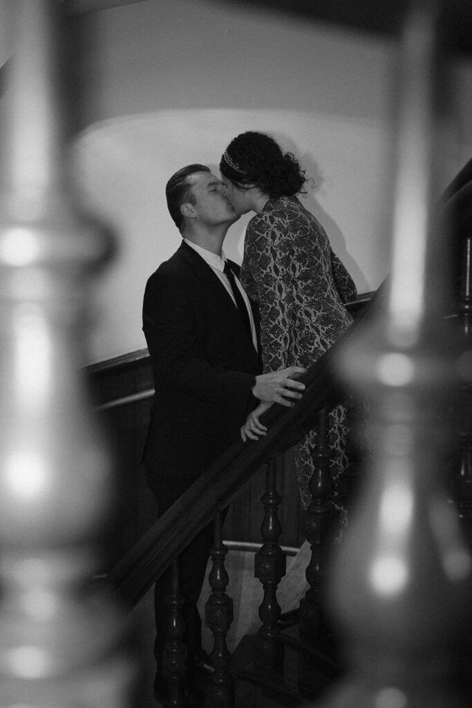 black and white photo with direct flash of fiances kissing on a staircase