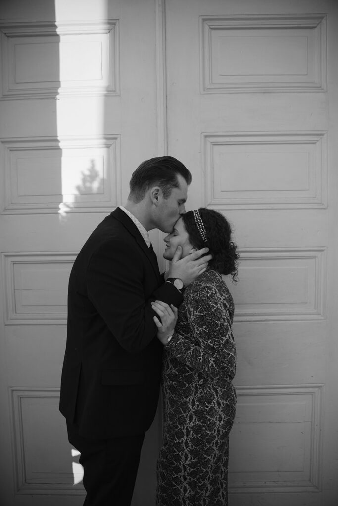black and white photo of man kissing his fiance on the forehead