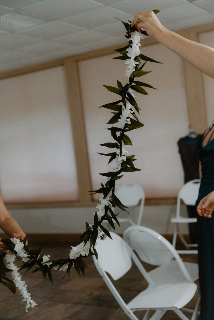 Photo of bride holding up the lei her groom is to wear