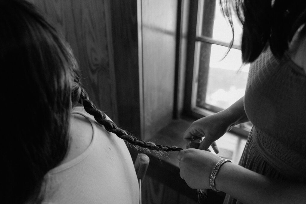 photo of groom's sister braiding his hair