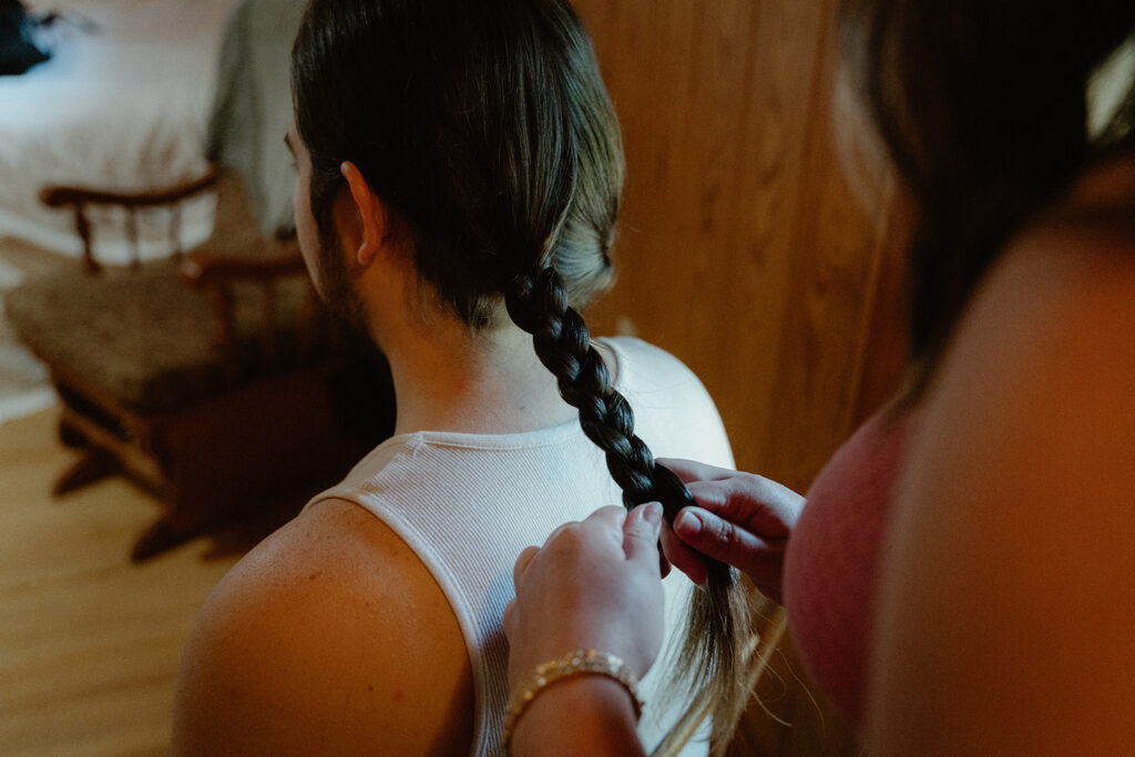 photo of groom's sister braiding his hair