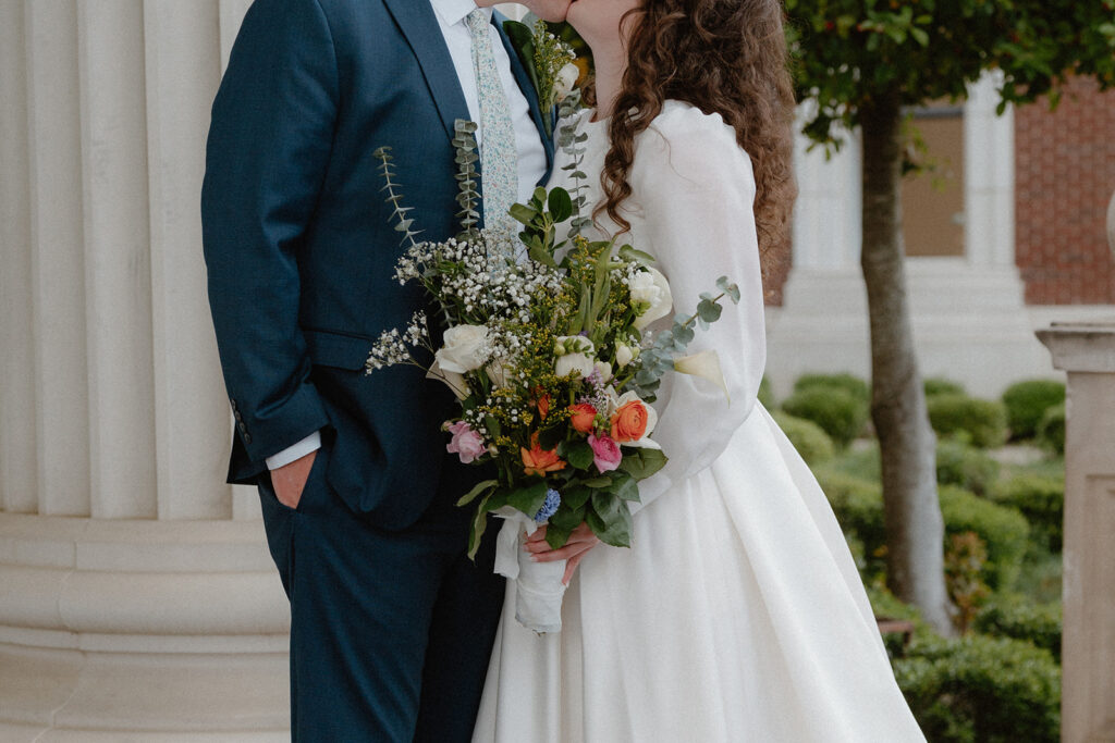 photo of bride and groom standing close with a bouquet