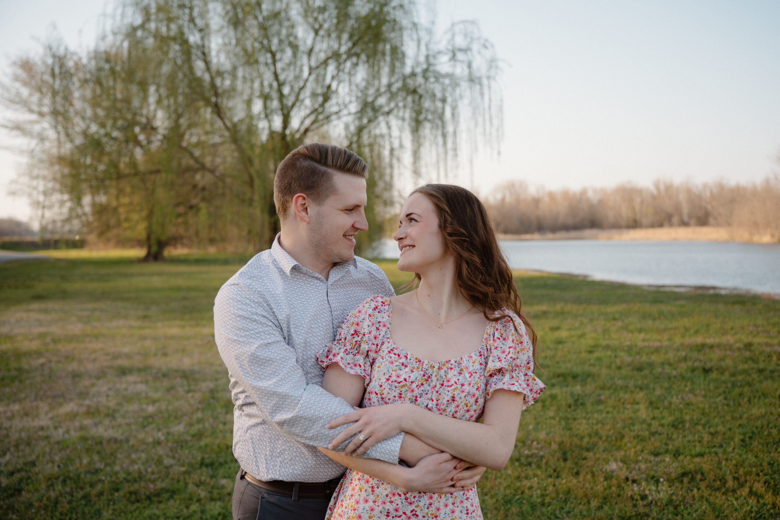 A couple hugging while looking at each other in front of a weeping willow
