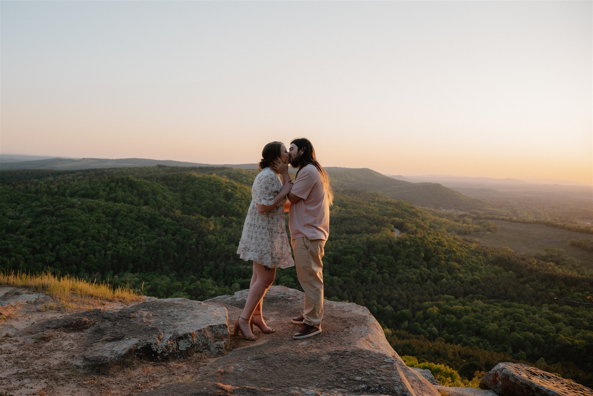 photo of engaged couple kissing on petit jean mountain