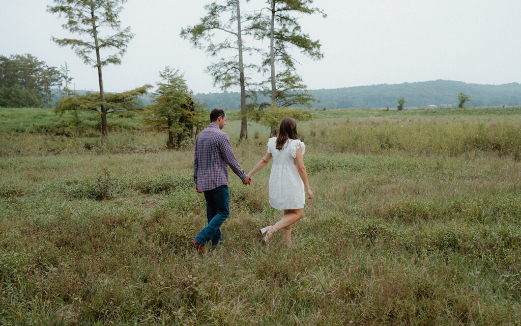 photo of engaged couple walking in tall grass