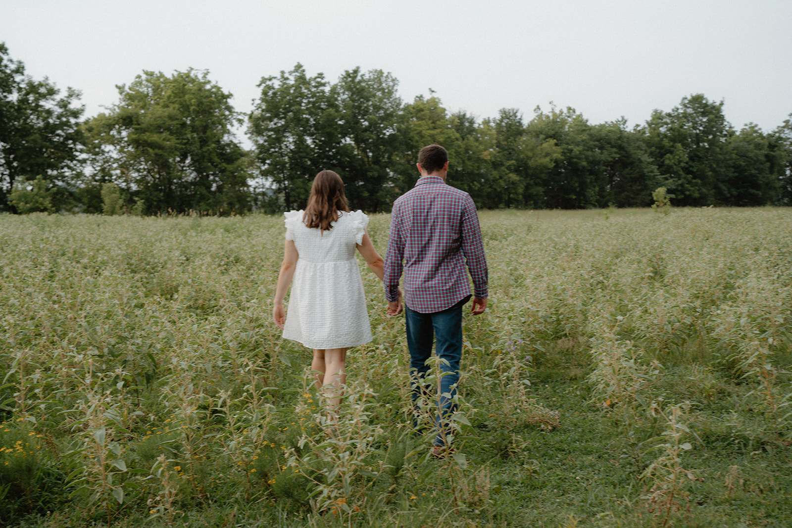 photo of engaged couple walking in tall grass near the arkansas river