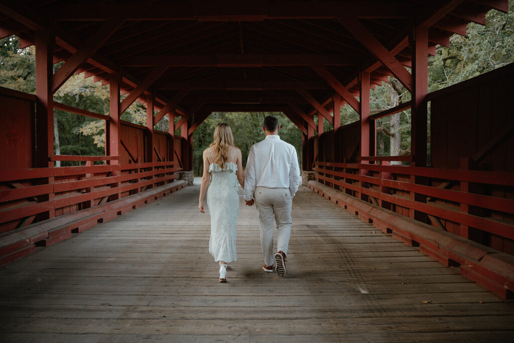 engaged couple walking on a covered bridge