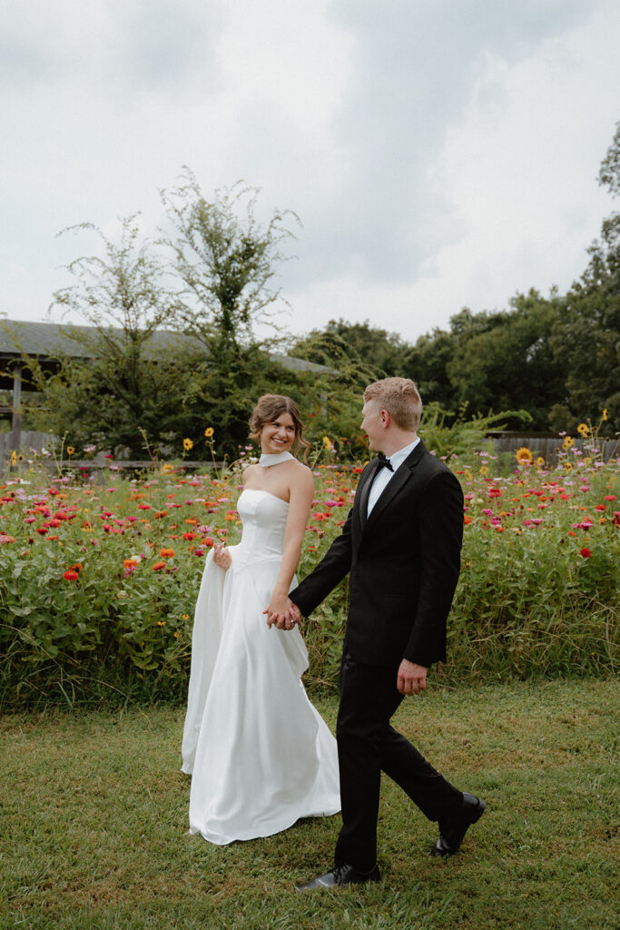 photo of bride and groom walking beside flower field before getting married in Arkansas