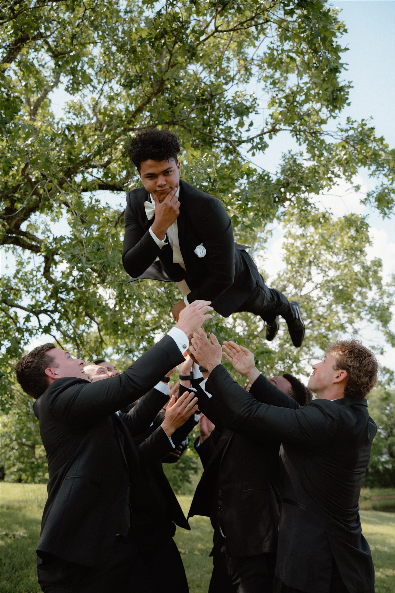 Photo of groom being thrown into the air by his groomsmen