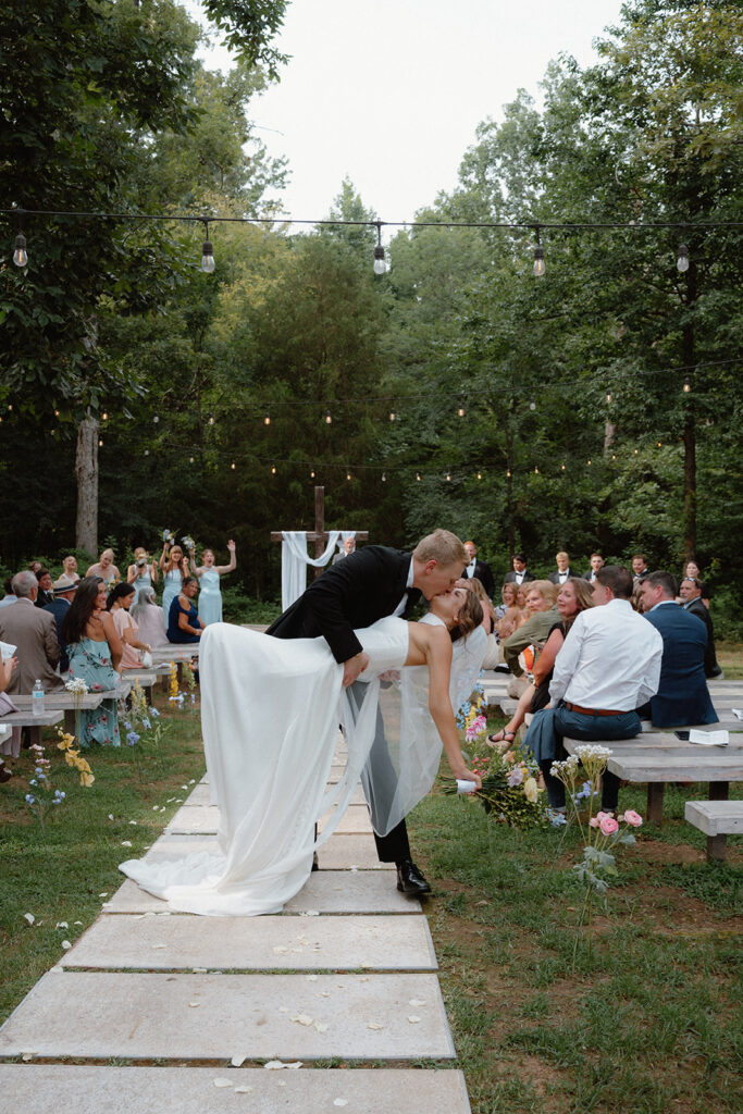 Photo of bride and groom  kissing down the aisle after getting married in Arkansas