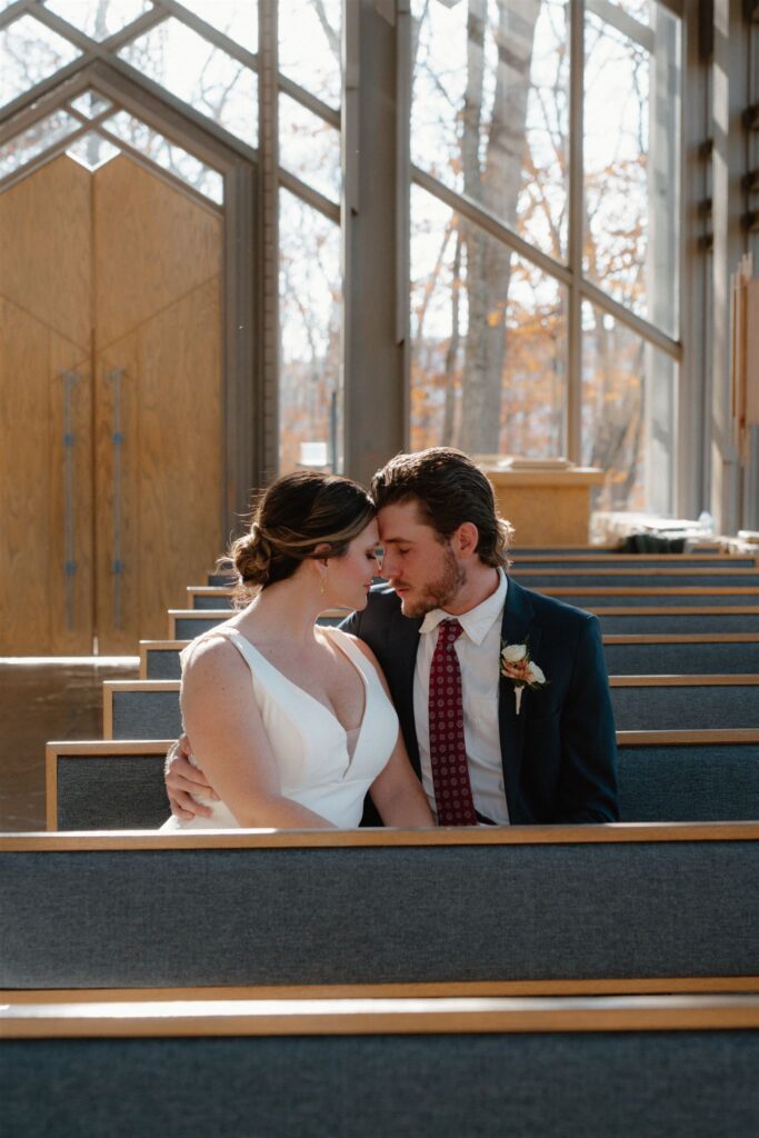 Photo of bride and groom sitting in Thorncrown Chapel in Arkansas after getting married