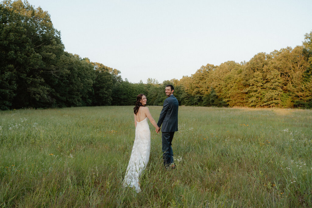 photo of a couple in bridal attire walking in a field