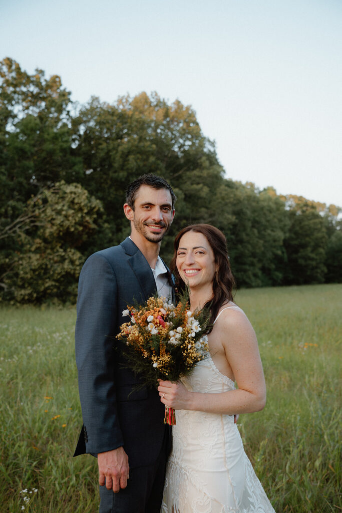 photo of a couple in bridal attire standing in a field