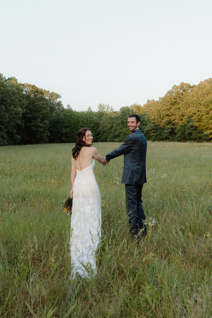 photo of a couple in bridal attire walking in a field